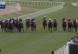 Group of thoroughbreds and jockeys in colorful silks racing neck-and-neck on a green turf track at Hawkesbury, with white railings and cheering crowd.