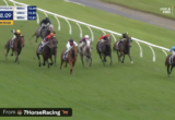 Horse race on a grassy track; multiple jockeys in bright silks ride around a bend as a line of white rails sweeps along, timer reads 2:28.09 with 220m to go, Morphettville R6 (Live & Free 7+).