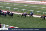Racing horses sprint along a green turf track in a Listed 1200m race; jockeys wear colorful silks.