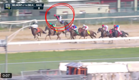 Jockey in a red cap appears mid-air above the track during a Belmont Park horse race (Race 8), with other horses close behind in the pack.