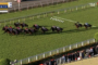 Horses race down a grass racetrack with a 100m marker; jockeys in colorful silks; crowd in stands along the fence; timer shows 1:12.17.