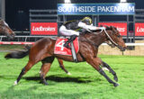 Nighttime horse race: two jockeys ride fast brown horses on a track with Ladbrokes signage in the background.
