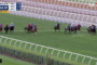 Horse race on a turf track with jockeys in colorful silks; race timer and distance graphics appear in the top-left, with a live broadcast watermark in the top-right.