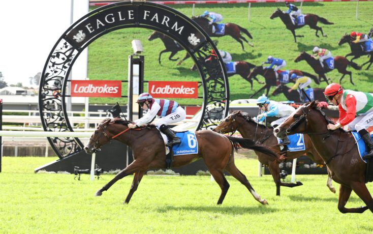 Horse race at Eagle Farm with jockeys in colorful silks; decorative arch reads 'Eagle Farm' and Ladbrokes banners in the background.