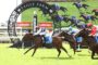 Horse race at Eagle Farm with jockeys in colorful silks; decorative arch reads 'Eagle Farm' and Ladbrokes banners in the background.