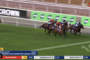 Horse race in progress at Flemington, several jockeys and horses close together on the track with a green infield.