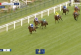 Live horse race at Royal Ascot: a lineup of galloping horses and jockeys in colorful silks racing along the green turf beside the white rails; live timer and race info shown on screen.