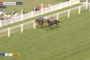 Two horses neck-and-neck on a green turf track with white rails; jockeys in blue and orange; spectators in the background; live broadcast overlay visible (Royal Ascot). Description of race action and setting only, no extraneous details.