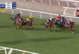 Horses racing on a turf track in a live broadcast; a leading horse with a pink cap on the right, others close behind, timer reads 1:03.99 and 160m to go.