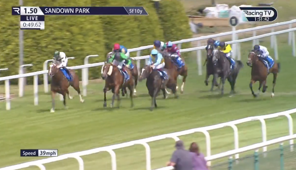 Horses race along the Sandown Park turf track with colorful jockey silks; live Racing TV overlay and a 39 mph speed readout.