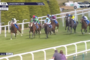 Horses race along the Sandown Park turf track with colorful jockey silks; live Racing TV overlay and a 39 mph speed readout.