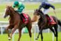 Two jockeys on racing horses leap the rails on a grassy track; green and blue silks, red saddlecloths visible.