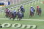Horse race in progress with jockeys on a curved track; scoreboard shows 2:15.13 and 280m to go, camera on leading pack.