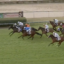 Demon Award wins Rockhampton Newmarket in thrilling finish | Just Horse Racing Group of racehorses with jockeys in colorful silks competing on a green turf track, near the rail; timer displayed in the top-right.