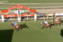 Horse race at Mackay Turf Club near the finish line, several jockeys on galloping horses with sponsor banners along the rails.
